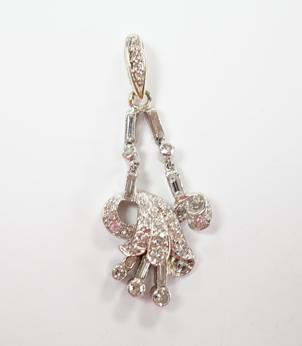 A white metal baguette and round cut diamond cluster set scroll pendant, overall 33mm, gross weight 3.6 grams.